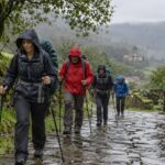 Peregrinos con chubasqueros en un sendero húmedo de Galicia