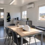 Comedor de una caseta modular de obra con mesa, sillas e iluminación natural