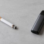 Cigarrillo apagado y dispositivo de vapeo sobre una mesa