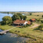 Una casa de campo con mucho terreno, cercana a una masa de agua (laguna, estanque...) y sin montañas.